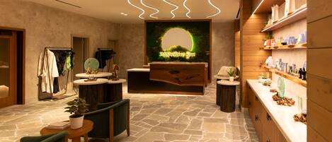Una spa con pavimento in pietra, arredi in legno, una reception e un cartello fissato al muro.