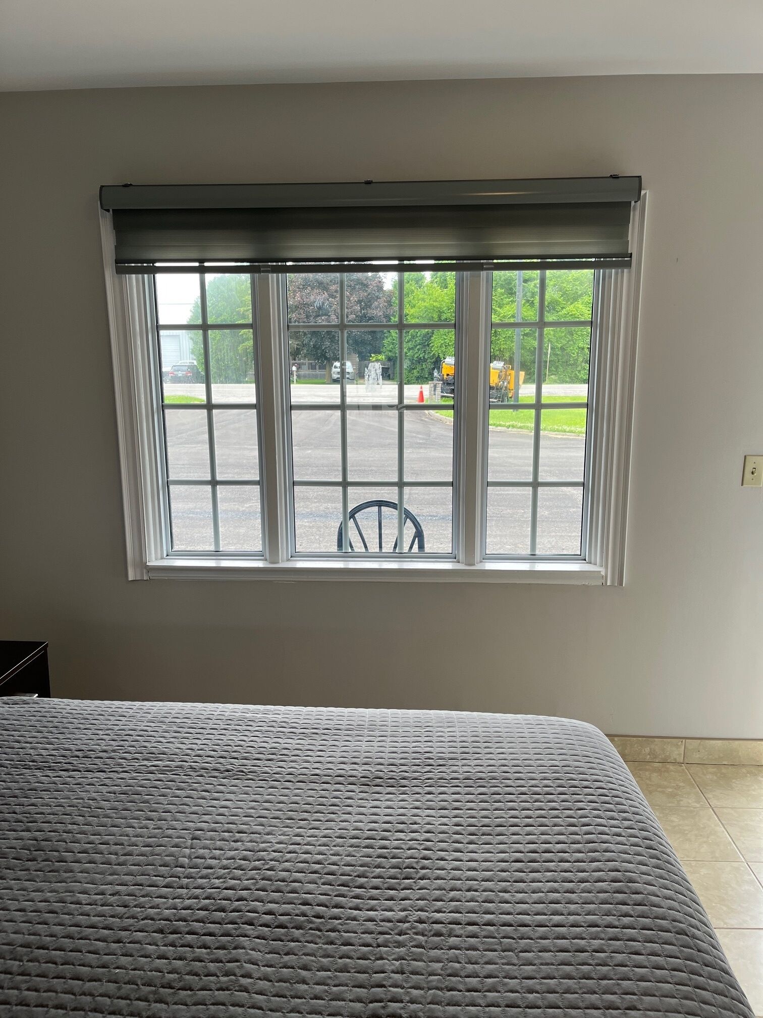 Una habitación con un ventanal grande, una cama y una silla.