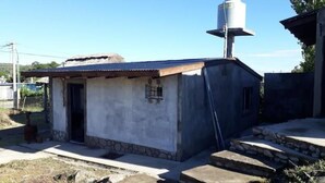 Una pequeña construcción con base de piedra, techo de metal y un tanque de agua en la parte superior.