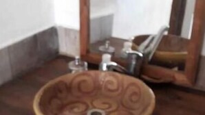 Un lavabo de cerámica marrón y redondo con un diseño decorativo, sobre una encimera de madera.