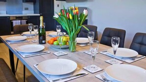 A dining table set with plates, cutlery, glasses, a bottle of champagne, and a bowl of fruit. - Quarry House, Aberporth (Aberporth)