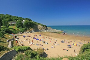 A beach with people sunbathing, tents, and a cliff with houses. - Quarry House, Aberporth (Aberporth)