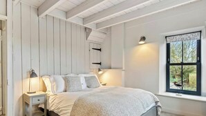 A bedroom with a bed, bedside lamps, a window with a view, and a wooden wall paneling. - Quarry House, Aberporth (Aberporth)