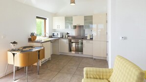 A compact kitchen with a dining area, a microwave, a kettle, and a sink. - Swn y Mor, Aberaeron (Aberaeron)