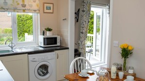 A compact kitchen with a washing machine, microwave, and a dining area with a table set for two.
