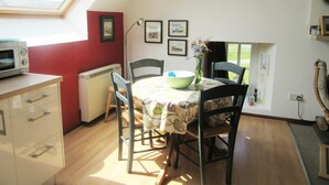 A dining area with a table set for two, a microwave, and a radiator.