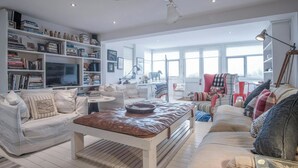 A spacious living room with a large bookshelf, a television, and a ceiling fan. - Ty Y Mor, Aberporth - Two Bedroom Cottage, Sleeps 4 (Aberporth)