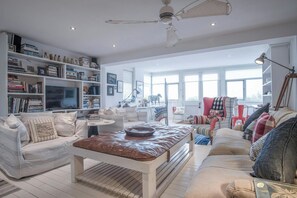 A spacious living room with a large bookshelf, a television, and a ceiling fan. - Ty Y Mor, Aberporth - Two Bedroom Cottage, Sleeps 4 (Aberporth)