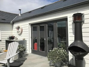 A house with a chimney, a large window, and a grill outside. - Ty Y Mor, Aberporth - Two Bedroom Cottage, Sleeps 4 (Aberporth)