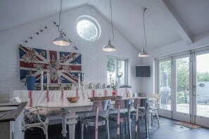 A dining area with a white table, chairs, and a flag on the wall. - Ty Y Mor, Aberporth - Two Bedroom Cottage, Sleeps 4 (Aberporth)