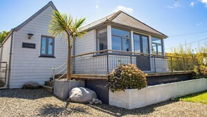 A two-story house with a balcony, a palm tree, and a small garden. - Ty Y Mor, Aberporth - Two Bedroom Cottage, Sleeps 4 (Aberporth)