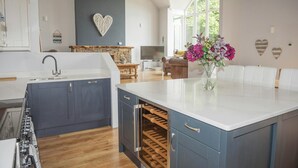 A modern kitchen with a central island, built-in oven, and a stone accent wall. - Stella Maris, Freshwater East (Freshwater East)