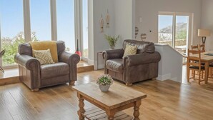 A spacious living room with two leather sofas, a wooden coffee table, and large windows offering a view of the outdoors. - Stella Maris, Freshwater East (Freshwater East)