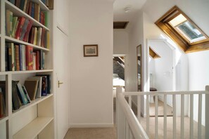 A hallway with a bookshelf, a framed certificate on the wall, a staircase with a white railing, and a skylight. - Garden Cottage, Newcastle Emlyn (Newcastle Emlyn)
