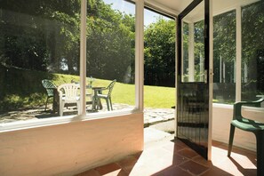 A patio with a table and chairs, a glass door, and a view of a grassy area.