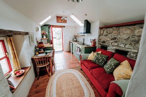 A cozy interior with a red sofa, a wooden dining table, and a kitchen area with a stone wall.