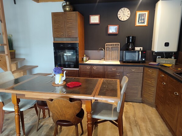 Una cocina moderna con armarios de madera, horno empotrado, microondas y cafetera.
