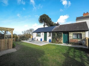 A two-story house with a stone exterior, a wooden deck, and a large tree in the backyard. - Y Gegin Fach, Cardigan (Rhos-hill)