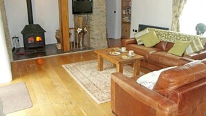 Una sala de estar acogedora con chimenea de piedra, sofá de cuero y una mesa de centro con platos.