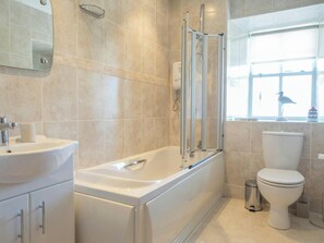 A modern bathroom with a bathtub, toilet, and a window with a view.