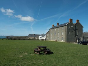 A large building with multiple windows and a grassy field in front.