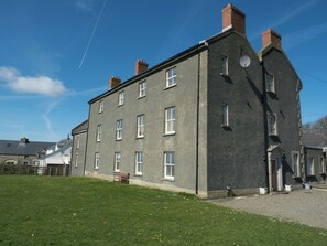 A two-story building with multiple windows, a satellite dish, and a grassy lawn.