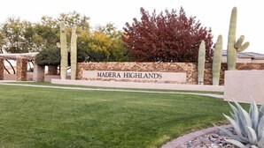 Un panneau indiquant « Madera Highlands », avec des cactus et une pelouse bien entretenue.