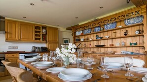 A wooden dining table set for six with white plates and glasses, surrounded by wooden chairs. - The Stables, Newgale (Llandeloy)
