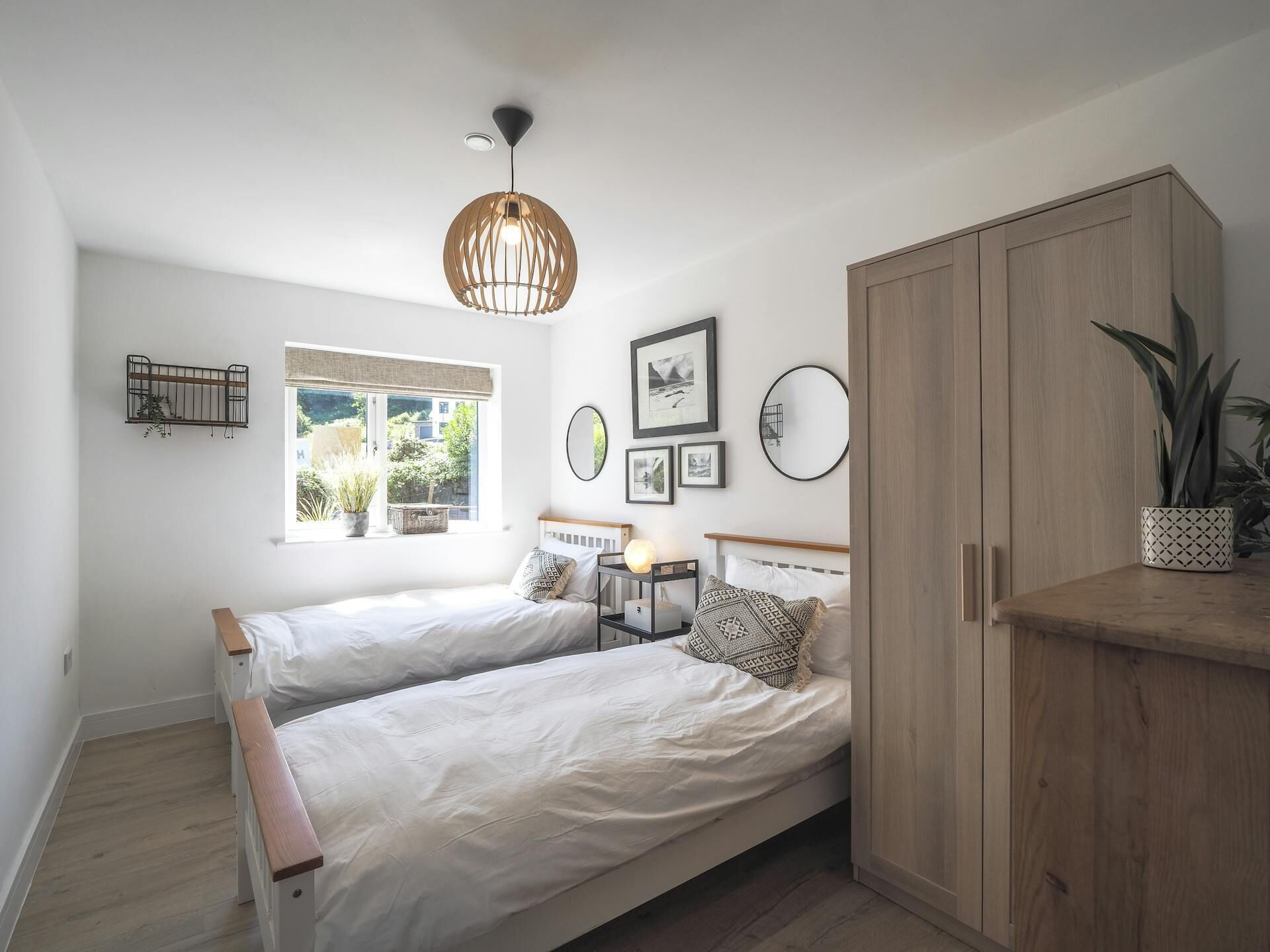 Une chambre avec deux lits, une armoire en bois, une fenêtre avec vue et des éléments de décoration fixés au mur.