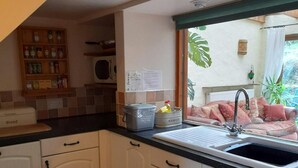 Een keuken met witte kastjes, een zwart aanrecht en een raam met uitzicht op een tuin.