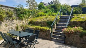 Een terras met een tafel en stoelen, een stenen muur en een trap.