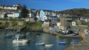 A coastal town with boats docked at a harbor, houses with colorful facades, and a stone wall along the waterfront. - No. 1 Cliffside, New Quay (New Quay)