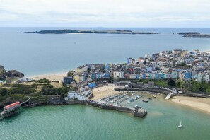 A coastal town with a harbor, sandy beach, and a fortified structure.