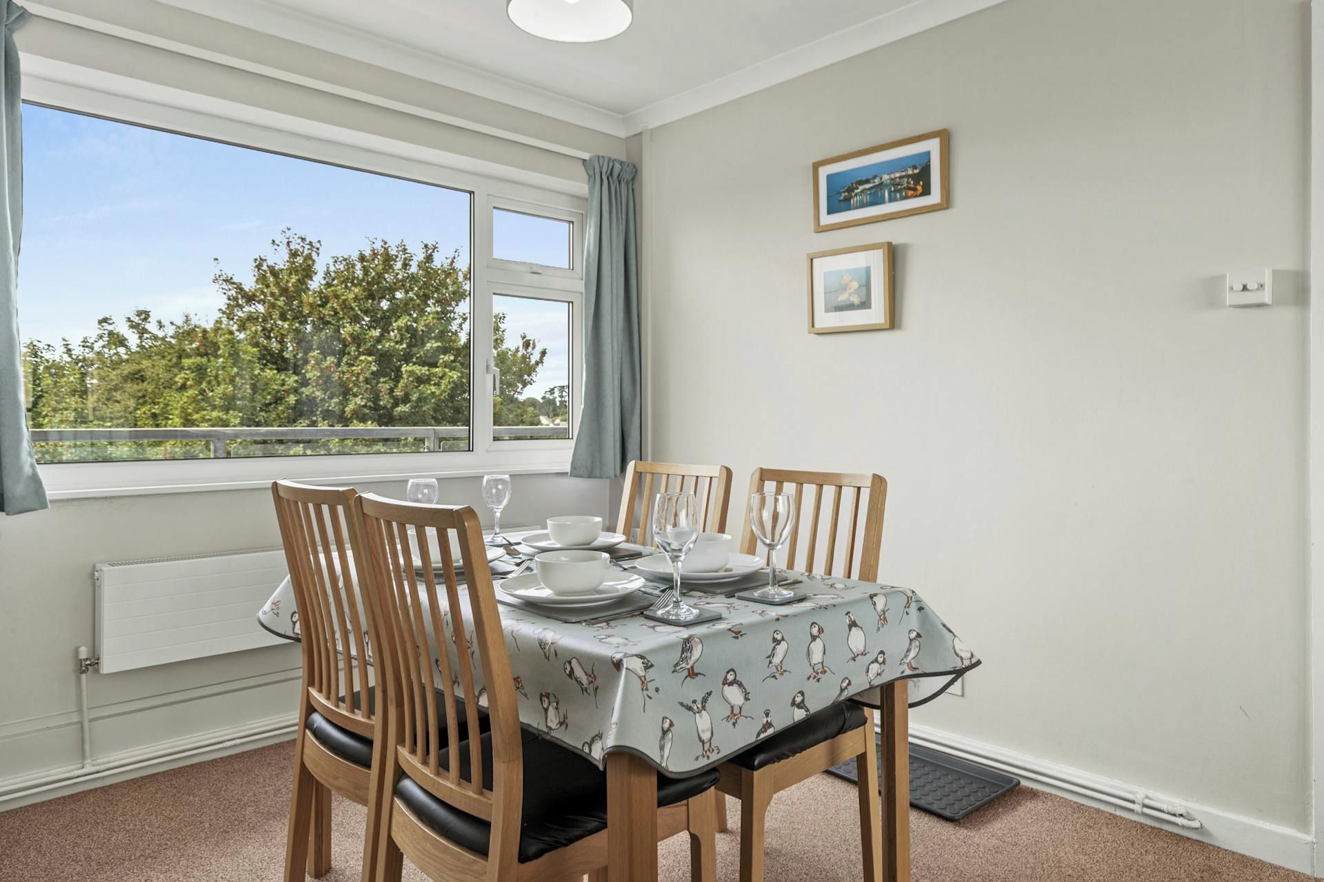 Dining table set for four by a window with green curtains