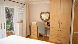 A bedroom with a bed, a desk with drawers, a chair, a wardrobe, and a heart-shaped mirror. - Vilureef, Broad Haven (Broad Haven)