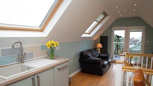 A modern kitchen with a skylight, a black leather sofa, and a dining area with a wooden table. - Vilureef, Broad Haven (Broad Haven)