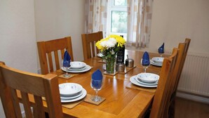 A dining table set with plates, glasses, and a vase of flowers.