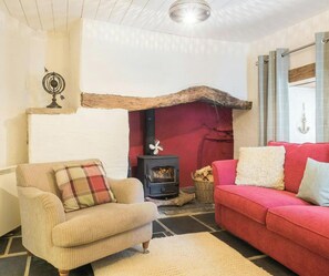 Una sala acogedora con chimenea, un sofá rojo, un sillón color beige y una alfombra estampada.