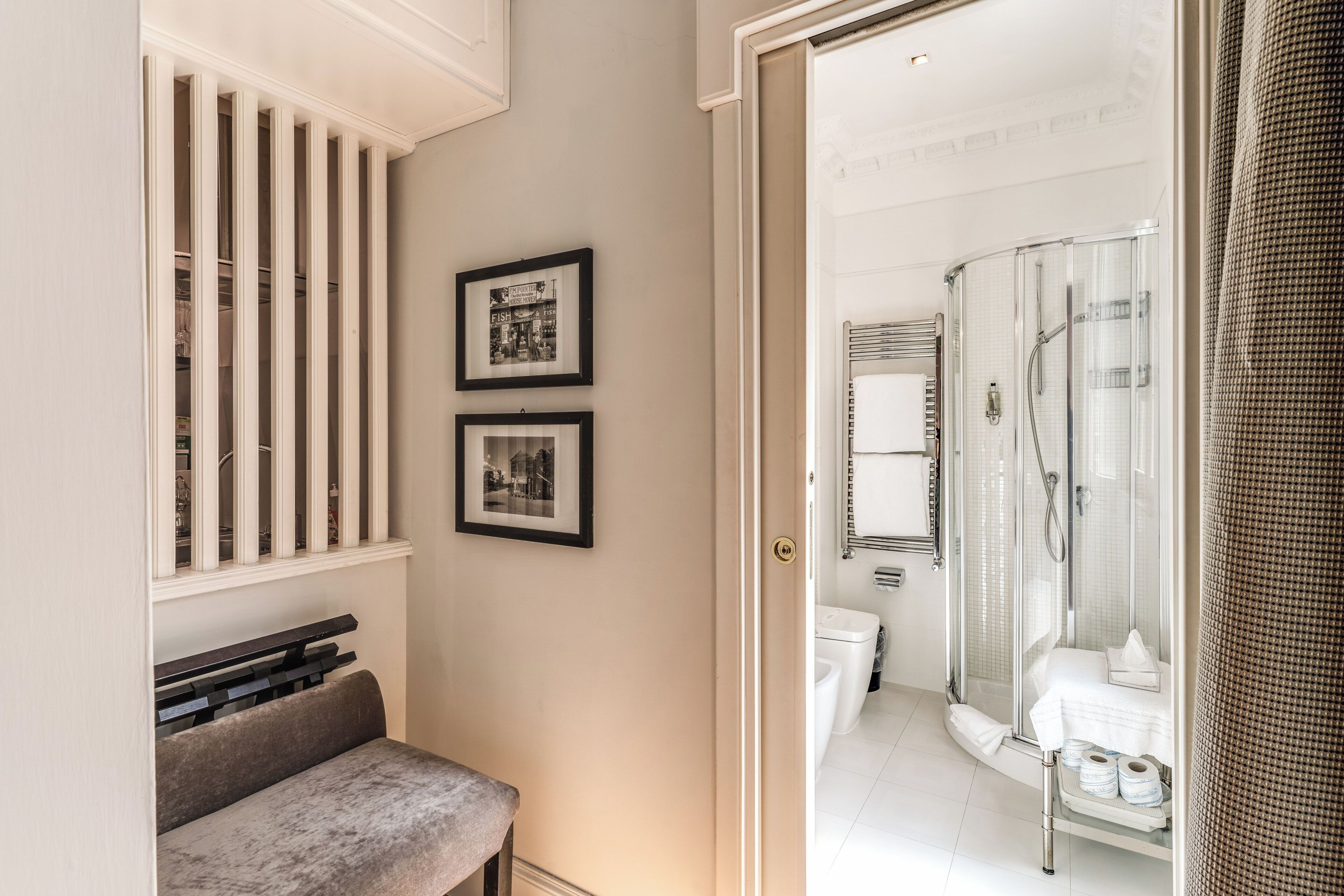 A modern bathroom with a glass-enclosed shower, a toilet, and a bench.