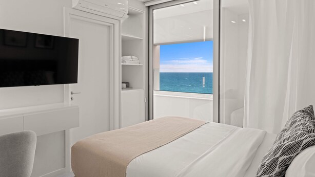 Une chambre moderne avec un lit, une télévision, une armoire et une vue sur la mer.