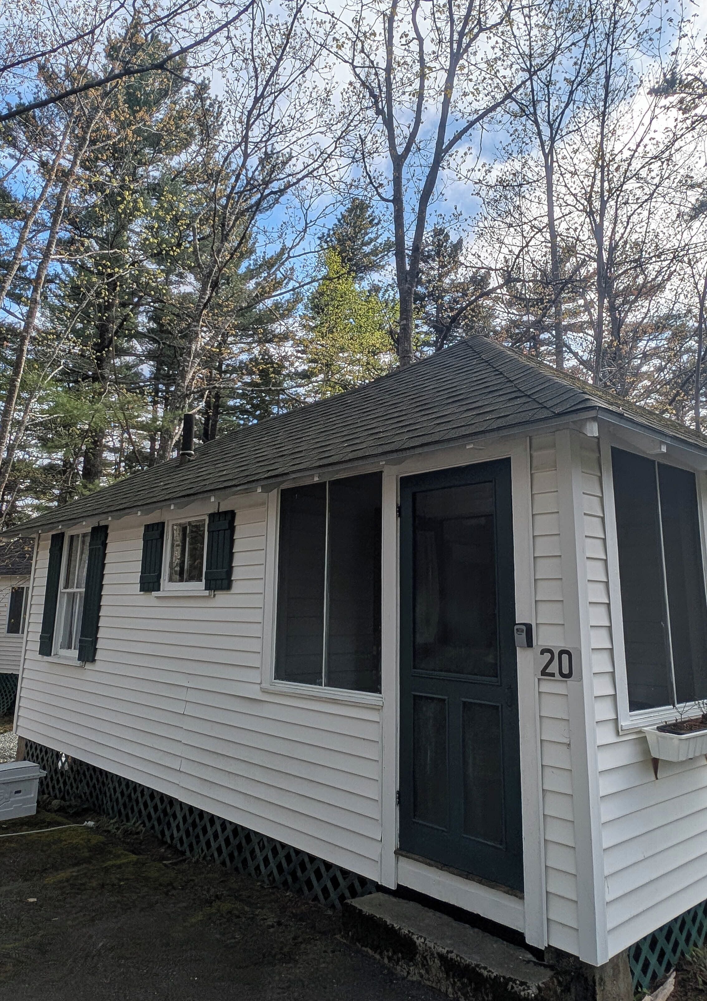 A single-story mobile home with a dark front door, numbered 20, and a small porch area.
