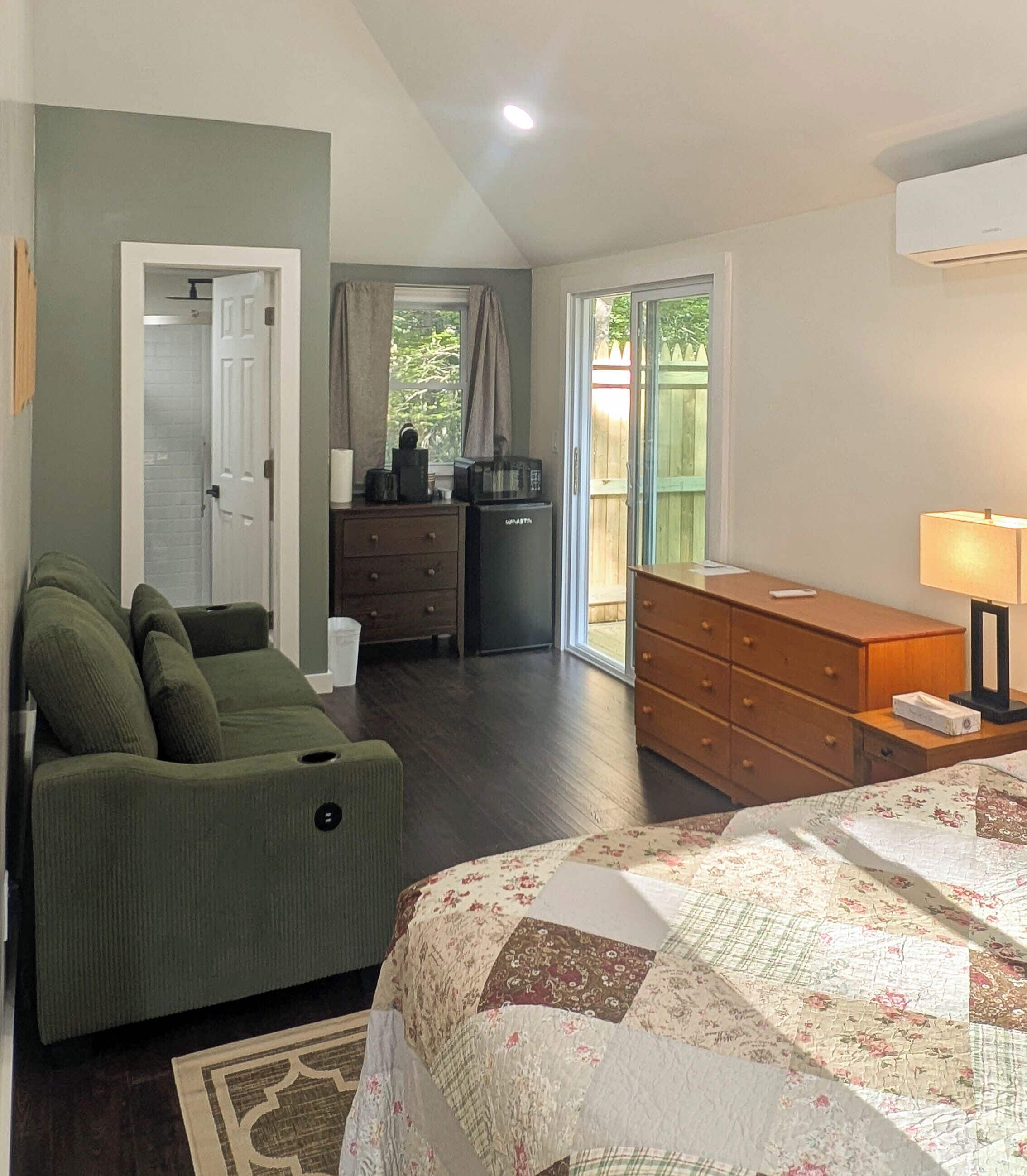 Une chambre comprenant un lit, une commode, un canapé et un coin cuisine.