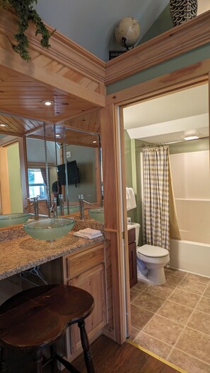 Une salle de bain avec un lavabo en verre, un meuble-lavabo en bois et des toilettes.