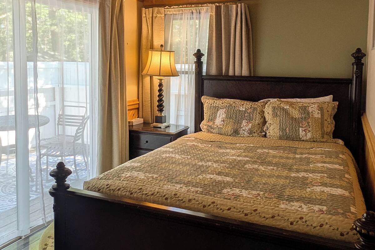 A wooden-paneled bedroom with a bed, curtains, and a nightstand.