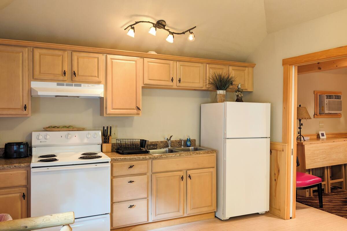 A kitchen with wooden cabinets, a white stove, a refrigerator, and a countertop with a sink.