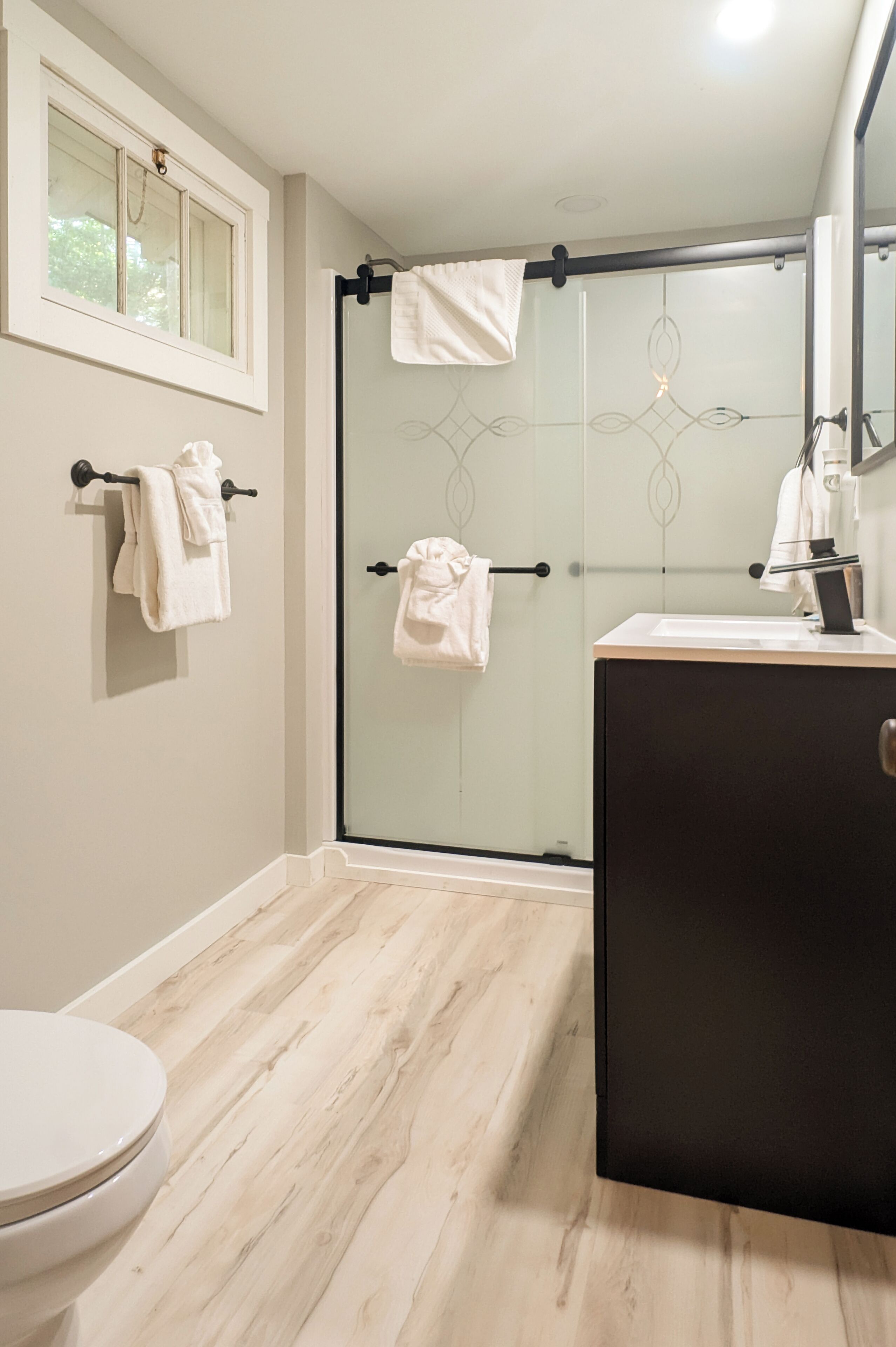 A bathroom with a toilet, a glass shower enclosure, and a vanity with a mirror.