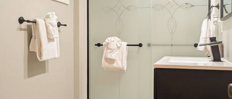 A bathroom with a toilet, a glass shower enclosure, and a vanity with a mirror.