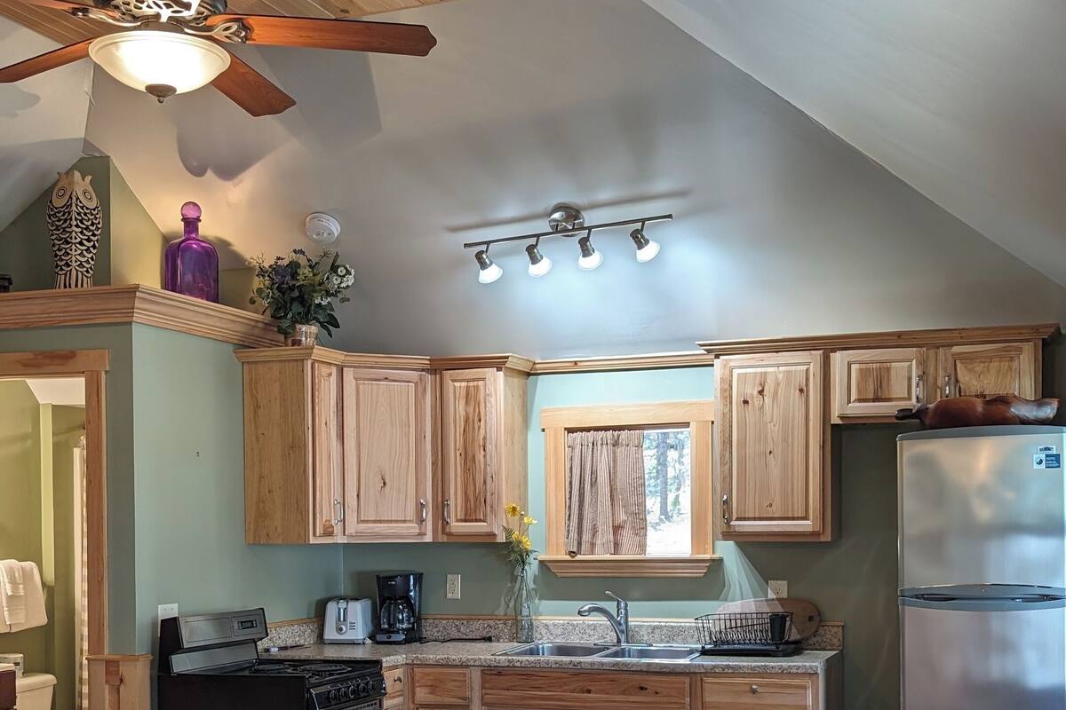 A kitchen with wooden cabinets, a stove, a refrigerator, and a ceiling fan.
