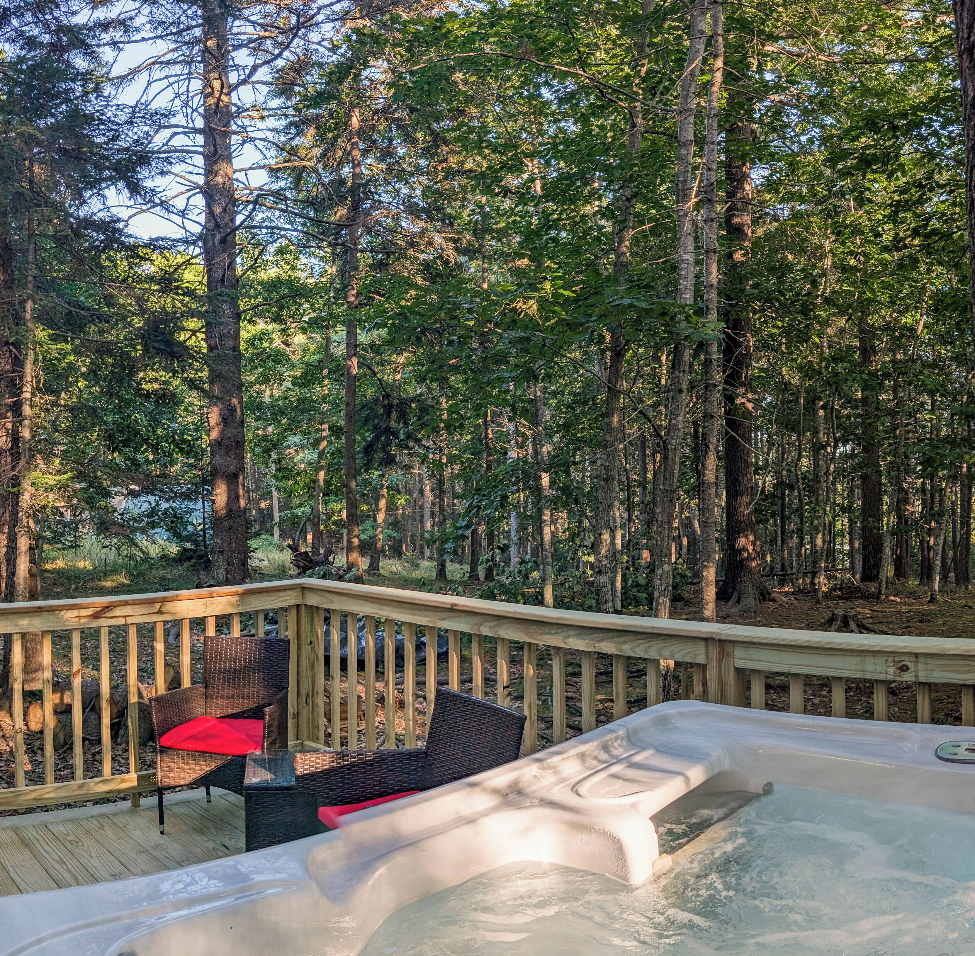 A hot tub on a wooden deck surrounded by a forest.