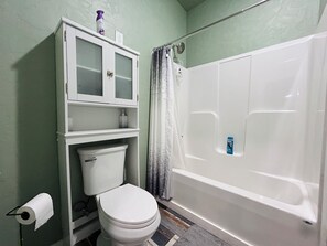 A bathroom with a toilet, a cabinet, a shower curtain, and a bathtub. - Winchester's Premier Downtown Loft! (Winchester)